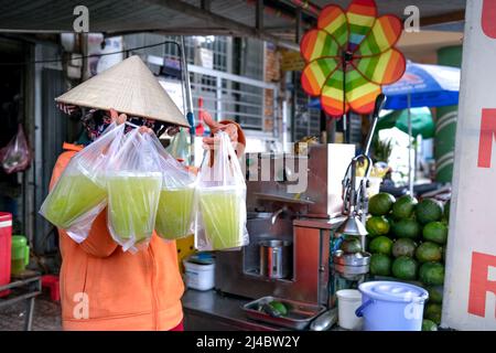 Ho Chi Minh City, Vietnam, 13 aprile 2022: Donna che spreme il succo di canna da zucchero. Popolare Street drink a ho Chi Minh City, Vietnam Foto Stock