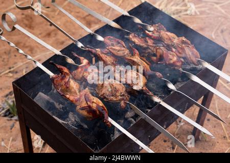 Preparazione di quaglia marinata sulla griglia grata. Foto di alta qualità Foto Stock