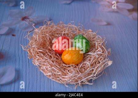 Uova di Pasqua in nido di paglia su sfondo blu Foto Stock