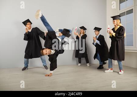 Felice università laureati in berretti e camici ballando e divertirsi il giorno della laurea Foto Stock