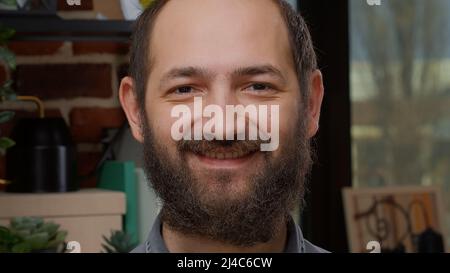 Ritratto dell'uomo caucasico con barba non rasata che sorride davanti alla macchina fotografica, mostrando un sorriso candido e denti bianchi. Modello maschile sensazione di fiducia e di avere espressioni facciali positive. Foto Stock