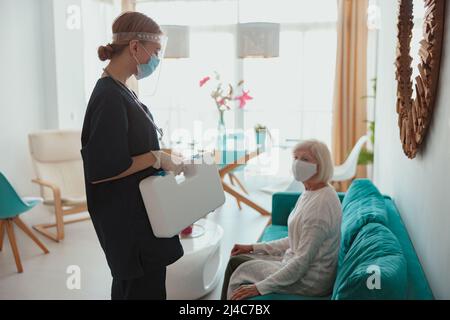 Donna anziana visitata da infermiera distrettuale a casa Foto Stock
