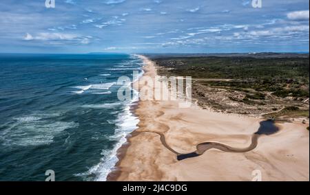 Vista con droni ad alto angolo di un'ampia e infinita spiaggia di sabbia dorata con un fiume che scorre verso l'oceano Foto Stock