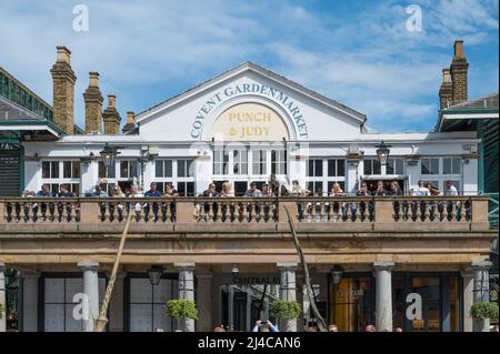 Persone sul balcone esterno del Punch & Judy pub socializzare e gustare bevande rinfrescanti in una calda giornata di sole. Covent Garden, Londra, Inghilterra, Regno Unito. Foto Stock