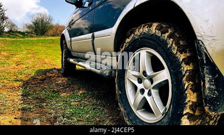 Ruota fangosa del veicolo fuoristrada. Veicolo fuoristrada parcheggiato su terreno sterrato. Foto Stock