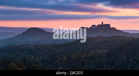 Vista dal Rennsteig sulla Foresta Turingia al Castello di Wartburg all'alba in autunno, vicino a Eisenach, Turingia, Germania Foto Stock