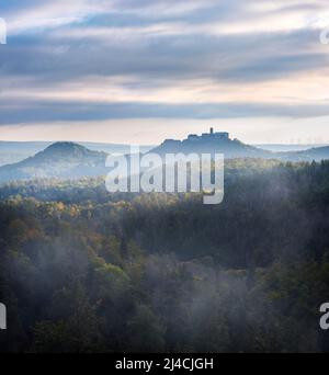 Vista dal Rennsteig sulla Foresta Turingia al Castello di Wartburg nella luce del mattino in autunno, nebbia che sorge, vicino a Eisenach, Turingia, Germania Foto Stock