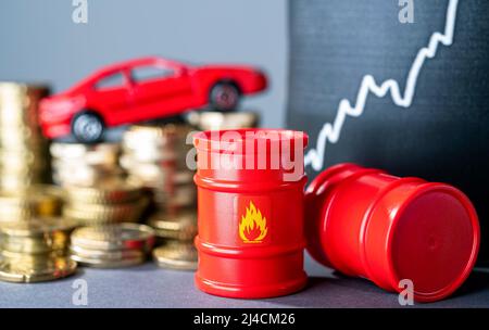 Barili rossi e auto, pile di denaro e una curva crescente che simboleggia i prezzi elevati del carburante Foto Stock