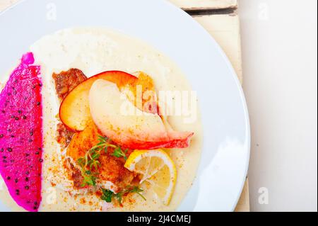 Filetto di orata di orata di orata di orata di mare in padella fritta con pruna di pesca fresca e fette di dragonfrutta di timo in cima Foto Stock