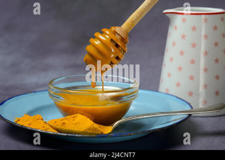 Miele d'ape con curcuma e curcuma in polvere, ingrediente per il latte d'oro, sana bevanda al latte Foto Stock