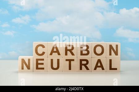 carbonio neutro. testo legno cubi carbonio neutro disposti su un tavolo bianco contro cielo blu con nuvole. Obiettivo netto zero emissioni di gas a effetto serra. Foto Stock