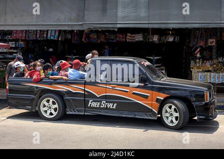 Thailandia, trasporto persone. Veicolo sovraccarico. Carrello raccoglitore completamente carico con persone che si trovano nella parte posteriore . Thailandia Sud-est asiatico Foto Stock