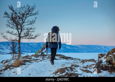 Giovane uomo in piedi in inverno ghiacciato natura e guardare l'inverno calmo nebbia tramonto. Concetto di pensiero, foto in piena libertà, bellissimo paesaggio. Ogoy isla Foto Stock