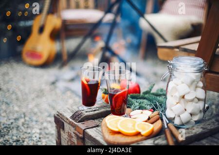 Due bicchieri di VIN brulé caldo con agrumi, mele, bastoncini di cannella, chiodi di garofano e anice su sfondo tavola di legno. All'aperto Foto Stock