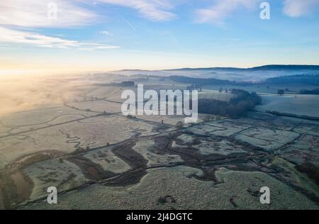 Misty Sunrise sopra le paludi e i prati ghiacciati, RSPB Exminster e Powderham Marshe da un drone, Exeter, Devon, Inghilterra Foto Stock