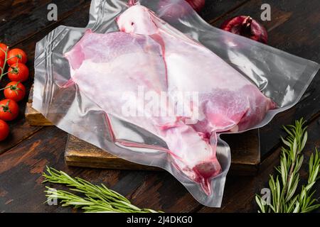 Coscia di tacchino in confezione di plastica sigillata, su vecchio sfondo di tavolo di legno scuro Foto Stock