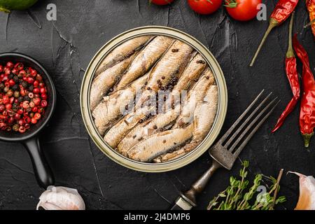 Gustoso pesce affumicato, sardine in scatola in olio, su sfondo nero tavolo di pietra scura, vista dall'alto piatto Foto Stock