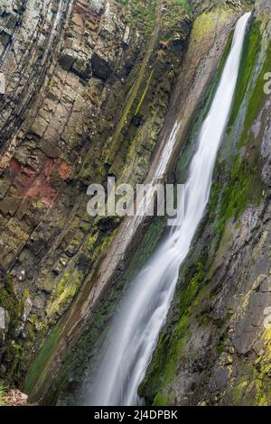 Ad una breve passeggiata attraverso le cime della scogliera da Hartland Quay si trova la cascata di Spoke's Mill Mouth. Le cascate si tuffano a 48 metri dalla cima alla spiaggia sottostante in t Foto Stock