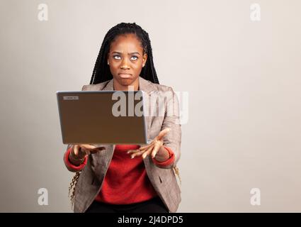 Giovane africano ragazza americana si arrabbia e getta portatile. Frustrazione con il concetto di tecnologia. Foto Stock