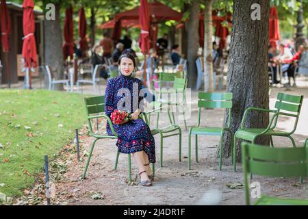 Donna attraente in un abito blu seduto nel parco Foto Stock