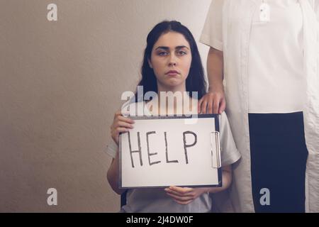 ragazza in depressione tenendo una compressa con l'iscrizione ''help e in piedi accanto al medico Foto Stock