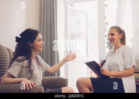 una ragazza graziosa con un sorriso dice al medico circa l'uscita di questa situazione. Foto Stock