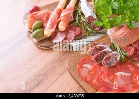 Antipasti italiani tradizionali su sfondo tavola in legno. Piatto di salumi con diversi tipi di salsicce - salame, bresaola, prosuito servito con Foto Stock