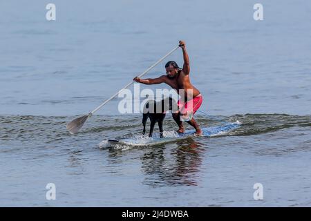 Provincia di Aurora, Filippine. 14th Apr 2022. Il surfista Mario Cardama Jr. E il cane Gordy surf in una spiaggia nella provincia di Aurora, nelle Filippine, 14 aprile 2022. Fondato nel 2016, il Dog Collective è costituito da appassionati di surf che sono anche amanti del cane. Trascorrono il loro tempo libero insegnando ai loro animali domestici adottisi a fare un giro in tavola da surf nel comune di Baler nella provincia di Aurora, che è localmente conosciuta come 'il luogo di nascita del surf delle Filippine.' Credit: Rouelle Umali/Xinhua/Alamy Live News Foto Stock