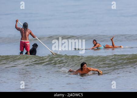 Provincia di Aurora, Filippine. 14th Apr 2022. Surfers e cane Gordy surf in una spiaggia nella provincia di Aurora, le Filippine, 14 aprile 2022. Fondato nel 2016, il Dog Collective è costituito da appassionati di surf che sono anche amanti del cane. Trascorrono il loro tempo libero insegnando ai loro animali domestici adottisi a fare un giro in tavola da surf nel comune di Baler nella provincia di Aurora, che è localmente conosciuta come 'il luogo di nascita del surf delle Filippine.' Credit: Rouelle Umali/Xinhua/Alamy Live News Foto Stock