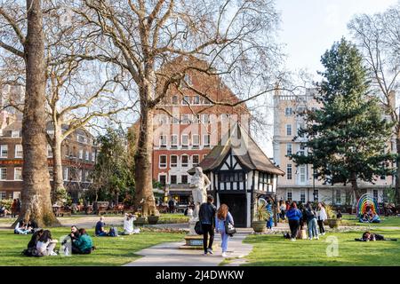 Persone che godono del tempo più caldo che arrivano nel Regno Unito, Soho Square, Londra, Regno Unito Foto Stock