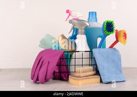 Cestino con prodotti per la pulizia sullo sfondo della parete con spazio per la copia. Servizio di pulizia. Detergenti e prodotti chimici per la casa. Spazio di copia Foto Stock
