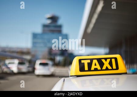 Fuoco selettivo sul cartello del taxi sul tetto dell'automobile contro il terminal dell'aeroporto. Foto Stock