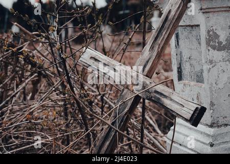 Croce di legno rovesciata e lapide danneggiate nel cimitero abbandonato. Vecchio cortile. Vandalismo del cimitero e concetto di riparazione della pietra. Messa a fuoco selettiva Foto Stock