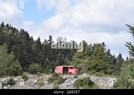 Abbandonato furgone rosso nella foresta, situato a Parnonas montagna, Kynouria sud. Escursioni e natura greca. Arcadia, Peloponneso, Grecia Foto Stock