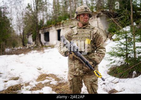 Un soldato britannico rimane allerta vicino ad un edificio distrutto nell'area di addestramento militare centrale di Tapa in Estonia sull'esercizio della NATO Drago grassetto accanto alle forze danesi e francesi. Data foto: Giovedì 14 aprile 2022. Foto Stock