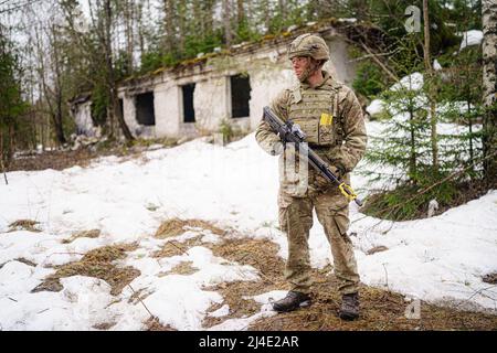 Un soldato britannico rimane allerta vicino ad un edificio distrutto nell'area di addestramento militare centrale di Tapa in Estonia sull'esercizio della NATO Drago grassetto accanto alle forze danesi e francesi. Data foto: Giovedì 14 aprile 2022. Foto Stock