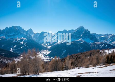 Vista panoramica della catena montuosa innevata e della foresta contro il cielo azzurro Foto Stock