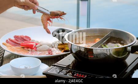 Shabu shabu o sukiyaki carne, manzo e frutti di mare in bollente hot pot vicino alla piscina Foto Stock