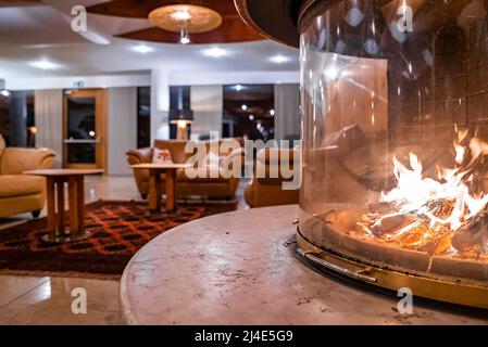 Primo piano di caminetto in vetro con divano sullo sfondo nella lussuosa lobby dell'hotel Foto Stock