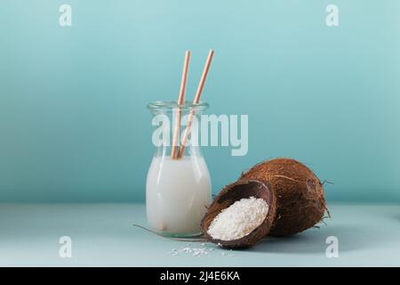 Bottiglia di latte vegano di cocco con paillette, cocco intero e fiocchi Foto Stock