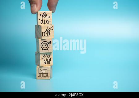 L'uomo d'affari mette un blocco di legno dei simboli di affari. Idee di marketing e pianificazione dei prodotti, startup, orientamenti di produzione dei prodotti. Foto Stock