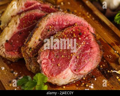 Appetitoso manzo crudo, bistecche di maiale cosparse di spezie su un tagliere di legno. Primo piano. Cibo biologico, carne della fattoria. Cibo sano, sano li Foto Stock