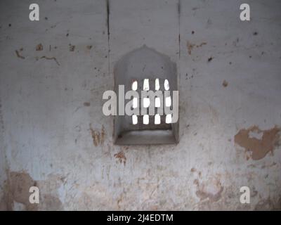 Una finestra con un traliccio di pietra in un'antica cella di prigione in India. Foto Stock