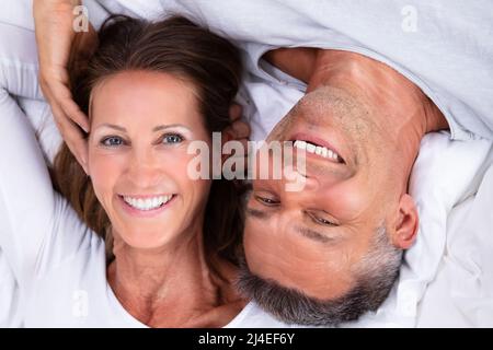 Angolo di Alta Vista di Felice Coppia Matura giacente sul letto Foto Stock