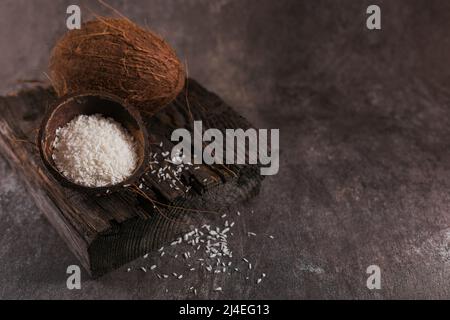 Cocco intero con scaglie di cocco su sfondo scuro Foto Stock