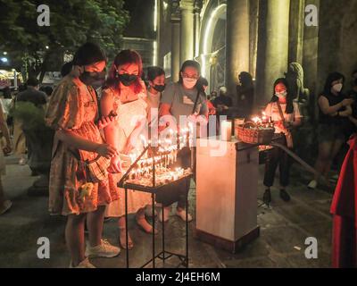 Manila, Filippine. 14th Apr 2022. Le devote femminili illuminano le candele e pregano in commemorazione del Giovedì di Maundy. I devoti cattolici nelle Filippine affollano la Chiesa di San Agustin ad Intramuros, Manila. Uno dei loro rituali è quello di visitare le diverse sette chiese o 'Visita Iglesia'. Esso commemora l'istituzione eucaristica di Gesù Cristo durante l'ultima cena con i suoi Apostoli. Credit: SOPA Images Limited/Alamy Live News Foto Stock