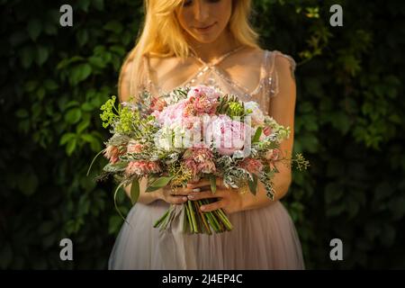 Ritratto di una donna elegante e irriconoscibile che indossa un abito da sposa grigio e posa in strada Foto Stock