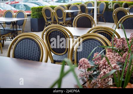 Tavoli e sedie puliti e vuoti al ristorante bar all'aperto circondato da piante e fiori. Foto Stock