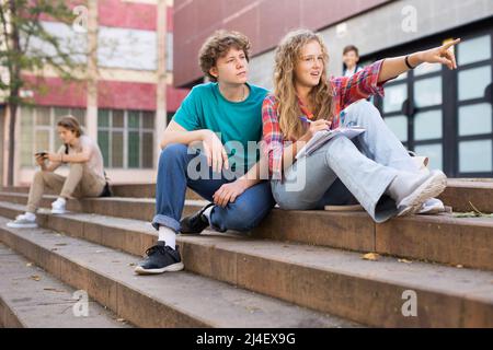 La ragazza punta la sua mano a qualcuno sulla strada a ragazzo durante la pausa in college Foto Stock