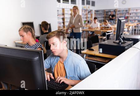 Studenti che usano il computer in lezione, insegnano loro Foto Stock